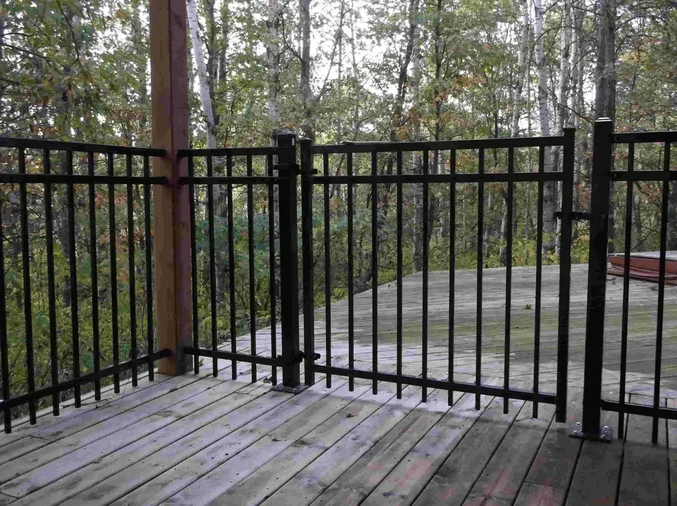 A wooden deck with a black fence surrounding it
