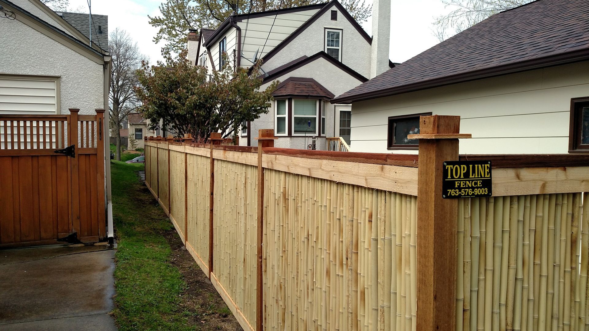 Wet residential alley with a wooden fence and houses in the background