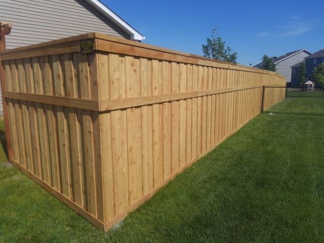 New wooden privacy fence along a grassy backyard beside a house