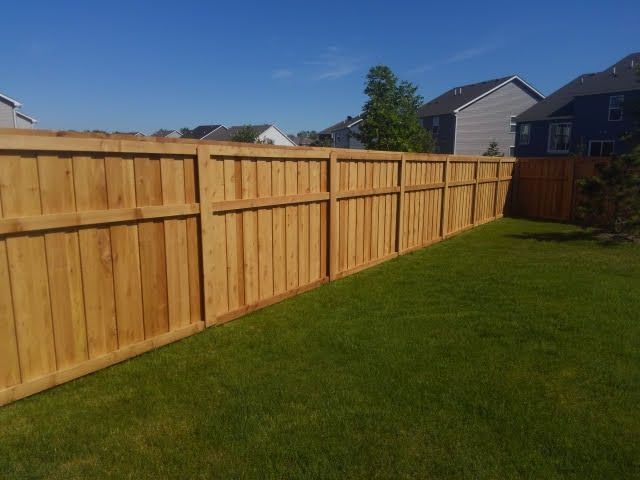 Wooden privacy fence along a green lawn under a clear blue sky