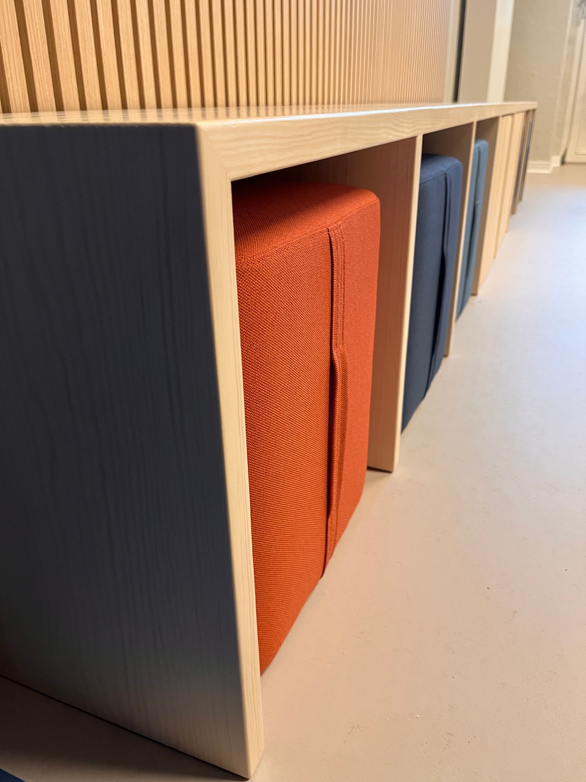 Sitzbank aus Massivholz Kiefer mit Sitzhockern in orange und blau.
