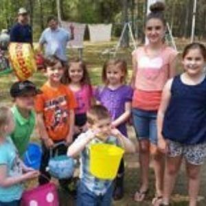 Children gathered outdoors for a group activity, holding colorful buckets and baskets.