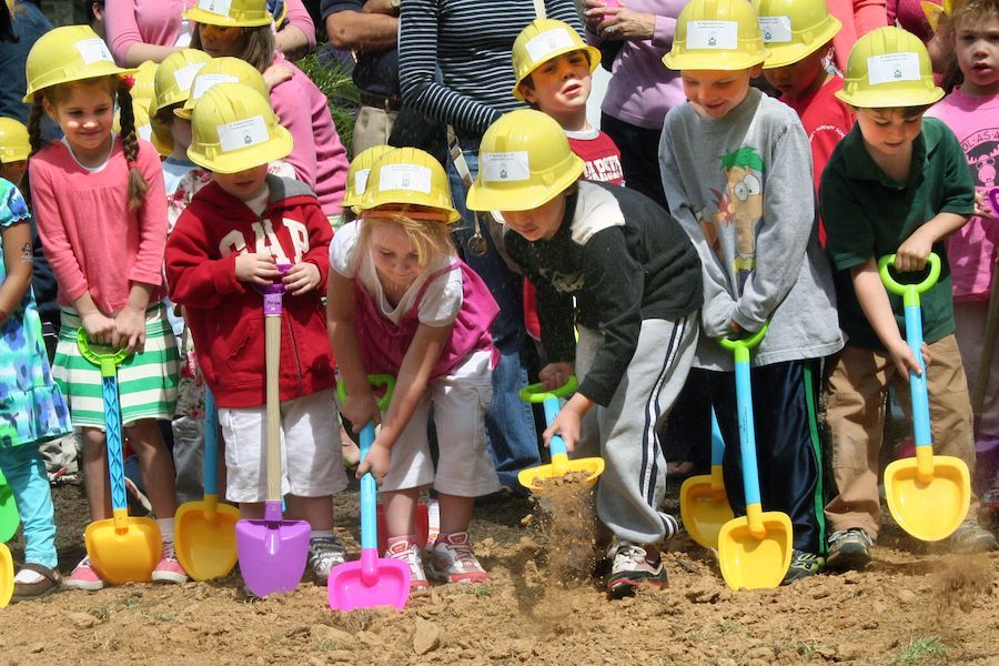 A group of children wearing hard hats and shovels