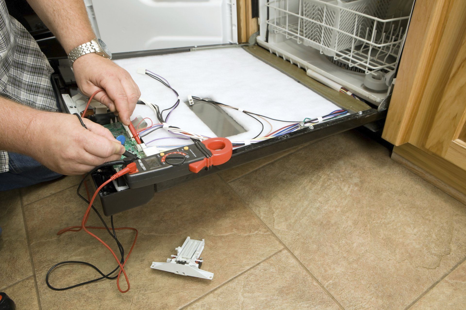 A man is working on a dishwasher in a kitchen