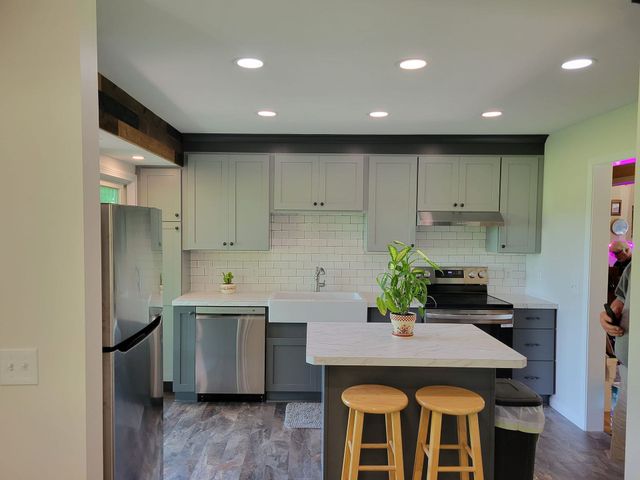 Empty room with gray wood-look flooring, blue walls, a wood barn door, and white trim.