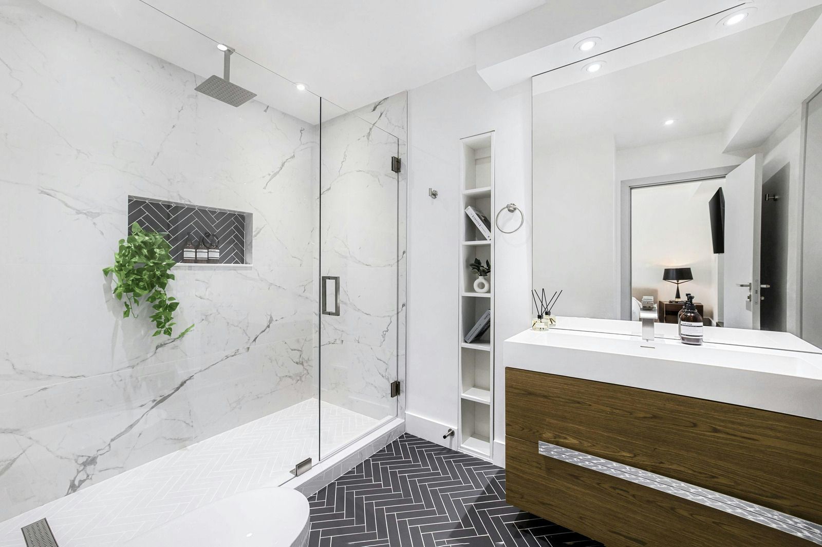 Modern bathroom with marble shower, glass door, and white vanity with wood-front cabinet