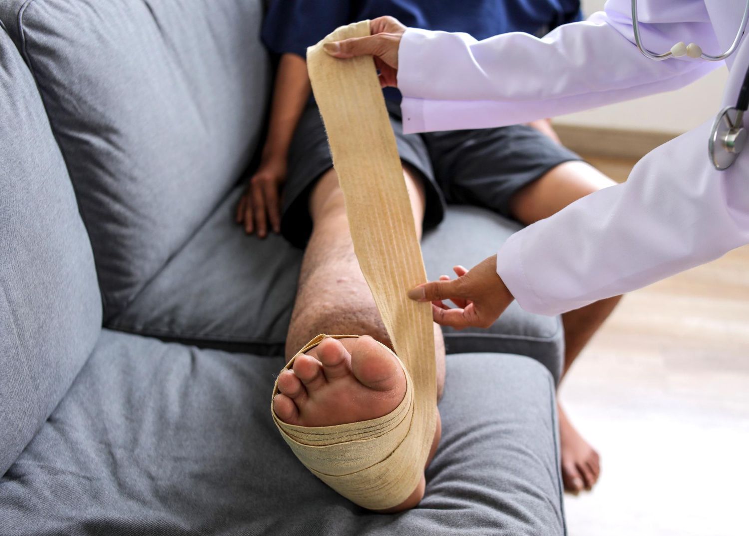 Doctor applying a leg cast to a patient resting on a couch