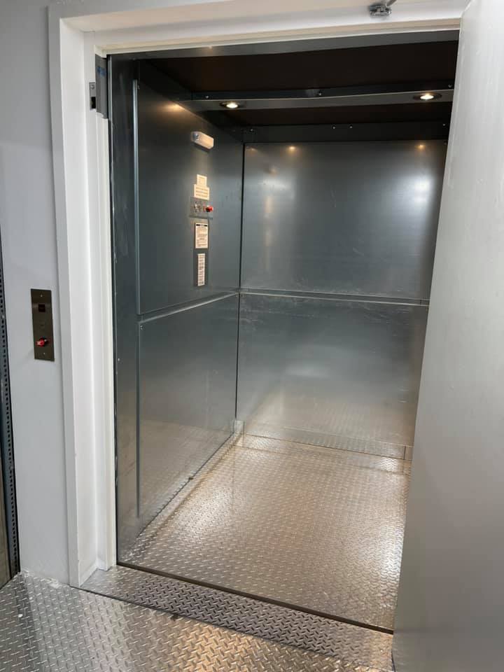 L'intérieur d'un ascenseur avec la porte ouverte et un plancher métallique.