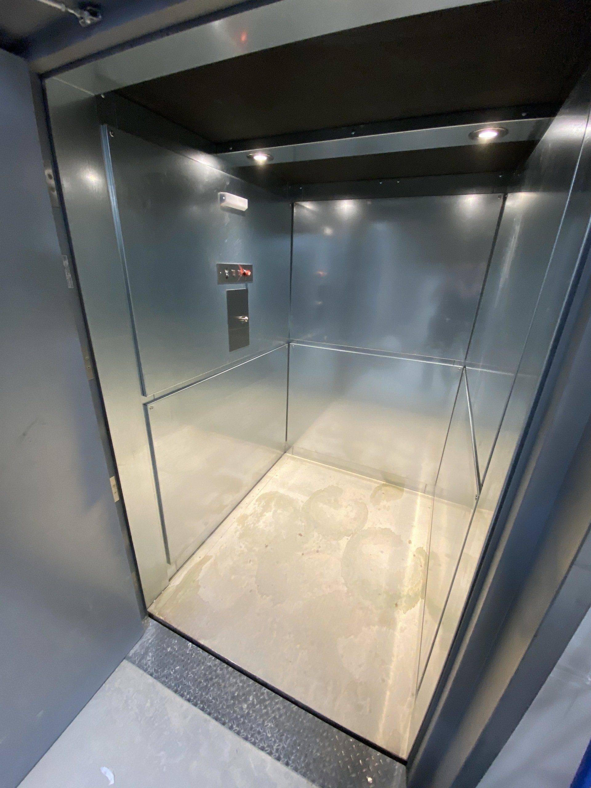 Un ascenseur vide avec un mur de verre et un sol en béton