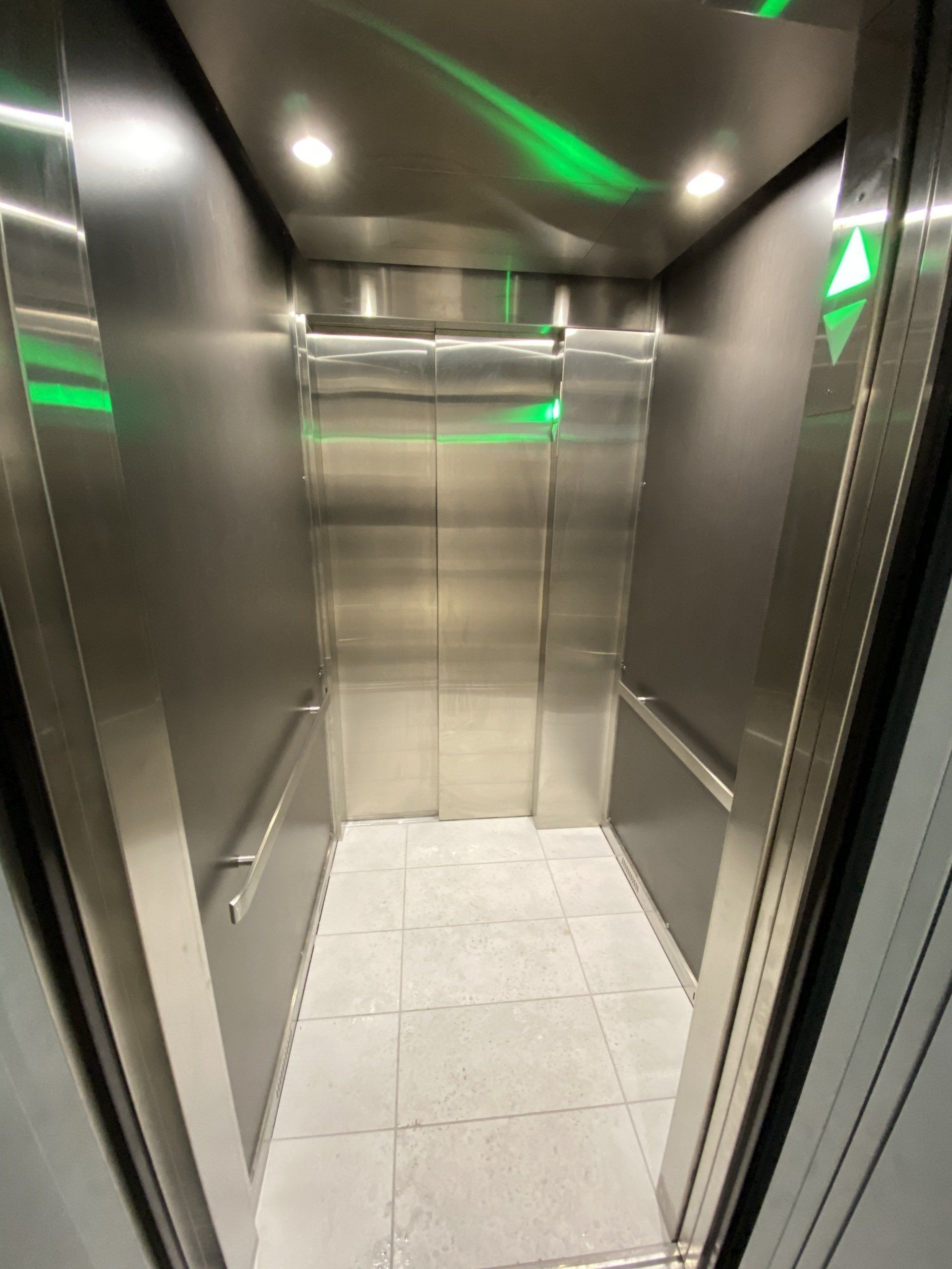 Un ascenseur en acier inoxydable avec un feu vert au plafond.