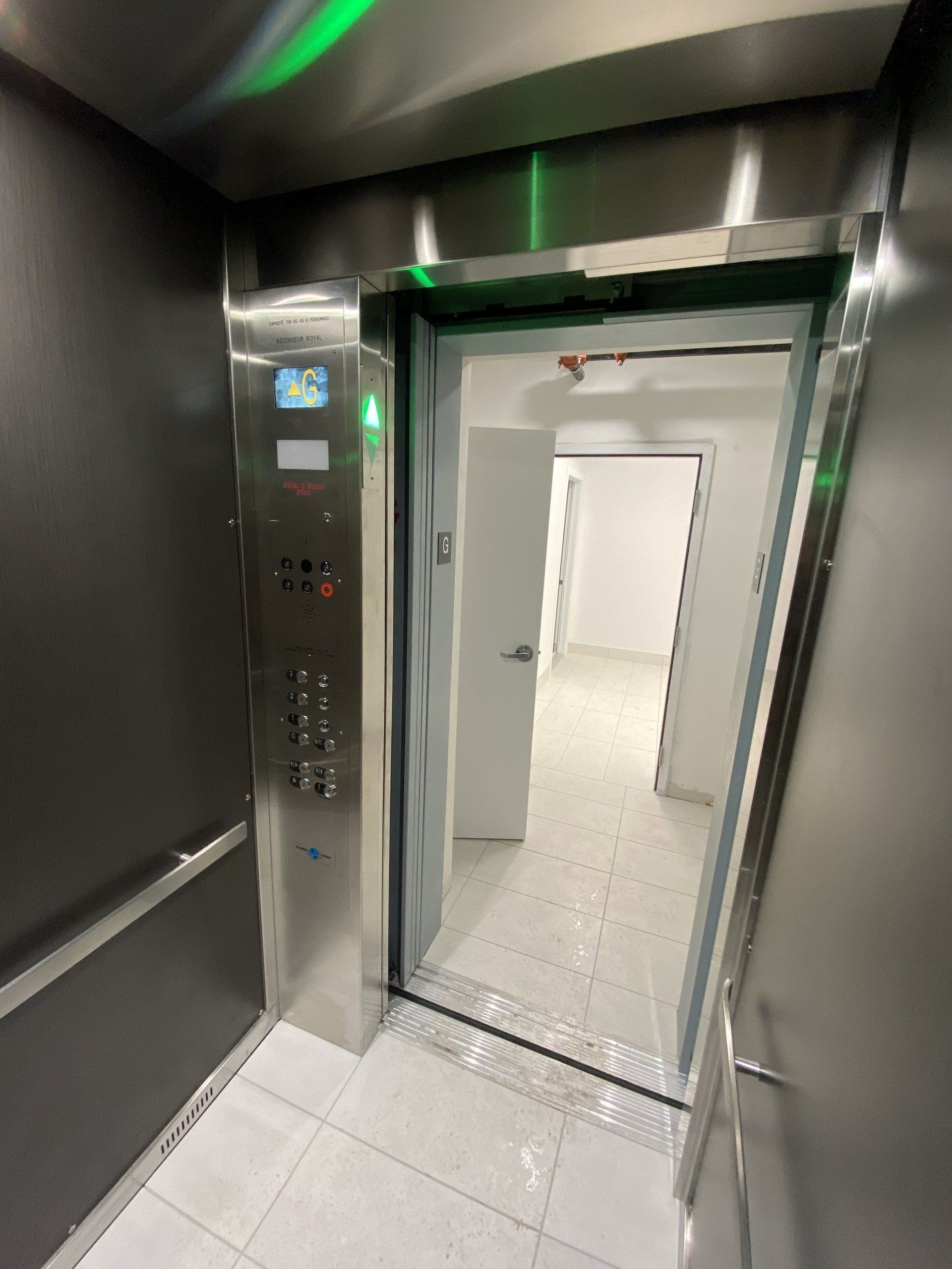 Un ascenseur avec une porte ouverte et un feu vert au plafond.