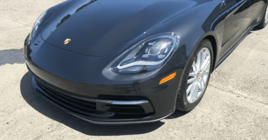Black Porsche sports car parked on pavement, front-left view
