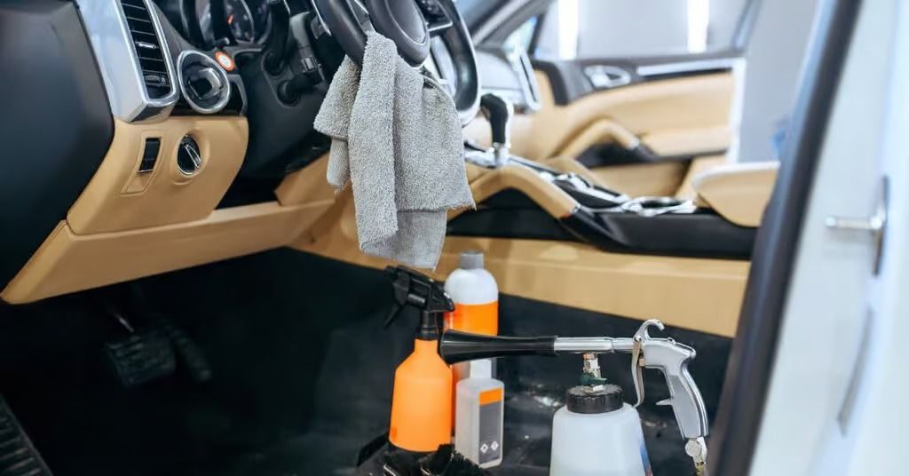 Car interior being detailed with cleaning spray bottles and cloths on the center console