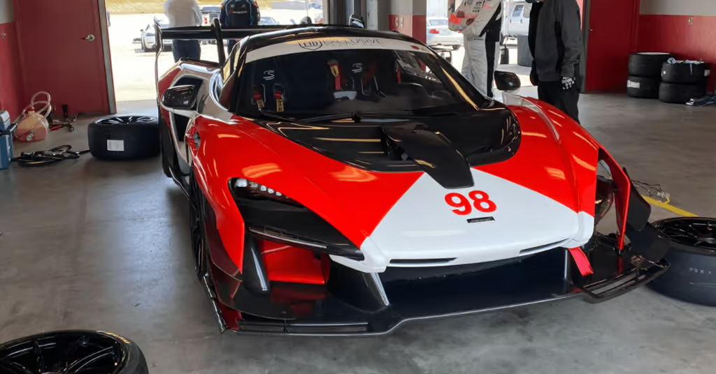 Red and white race car numbered 98 parked in a garage