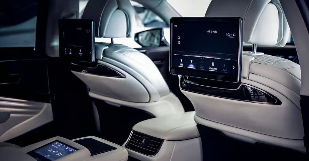 Luxury car interior with two rear-seat entertainment screens and a sleek white-and-black cabin