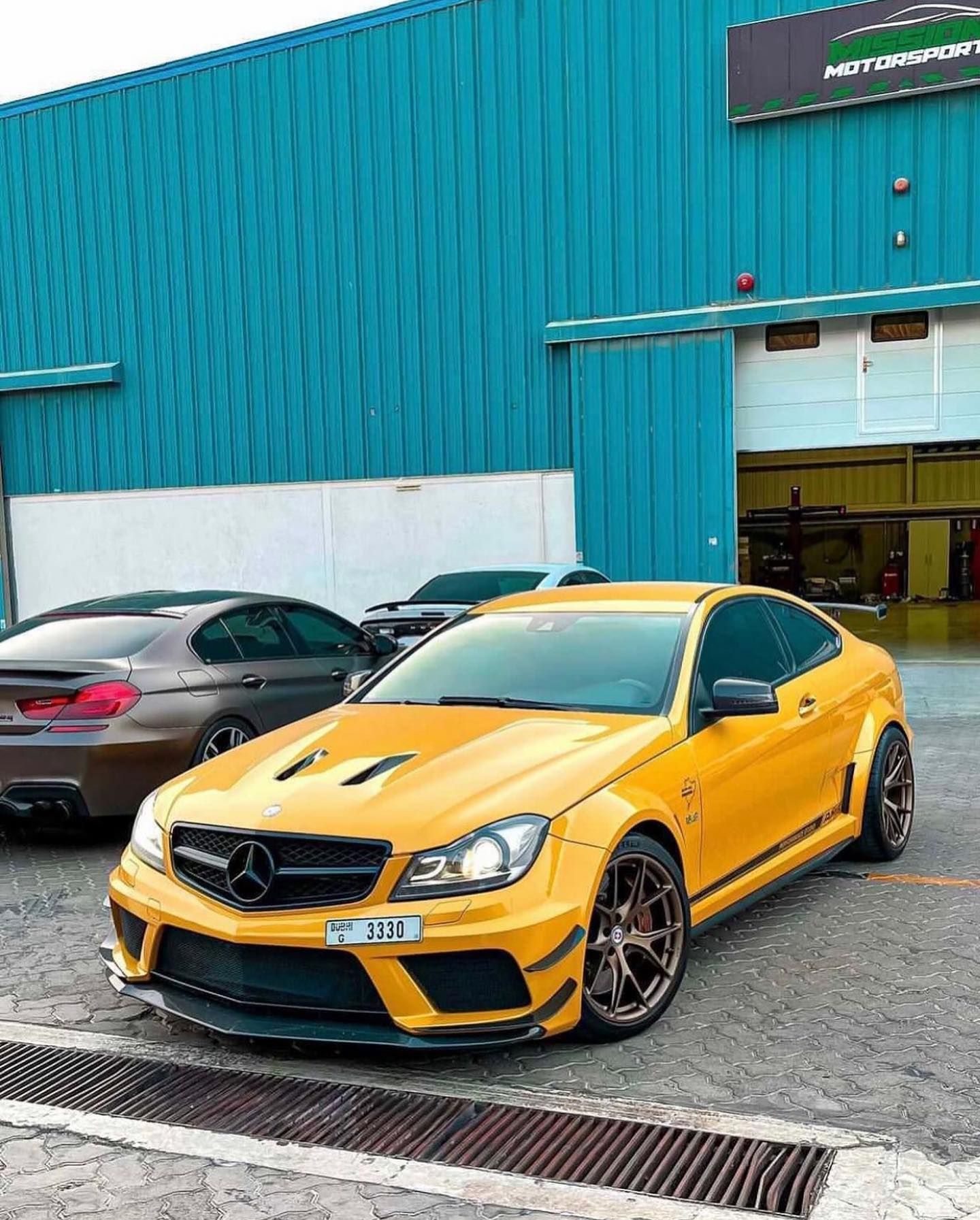 Yellow Mercedes sports car parked outside a blue industrial building