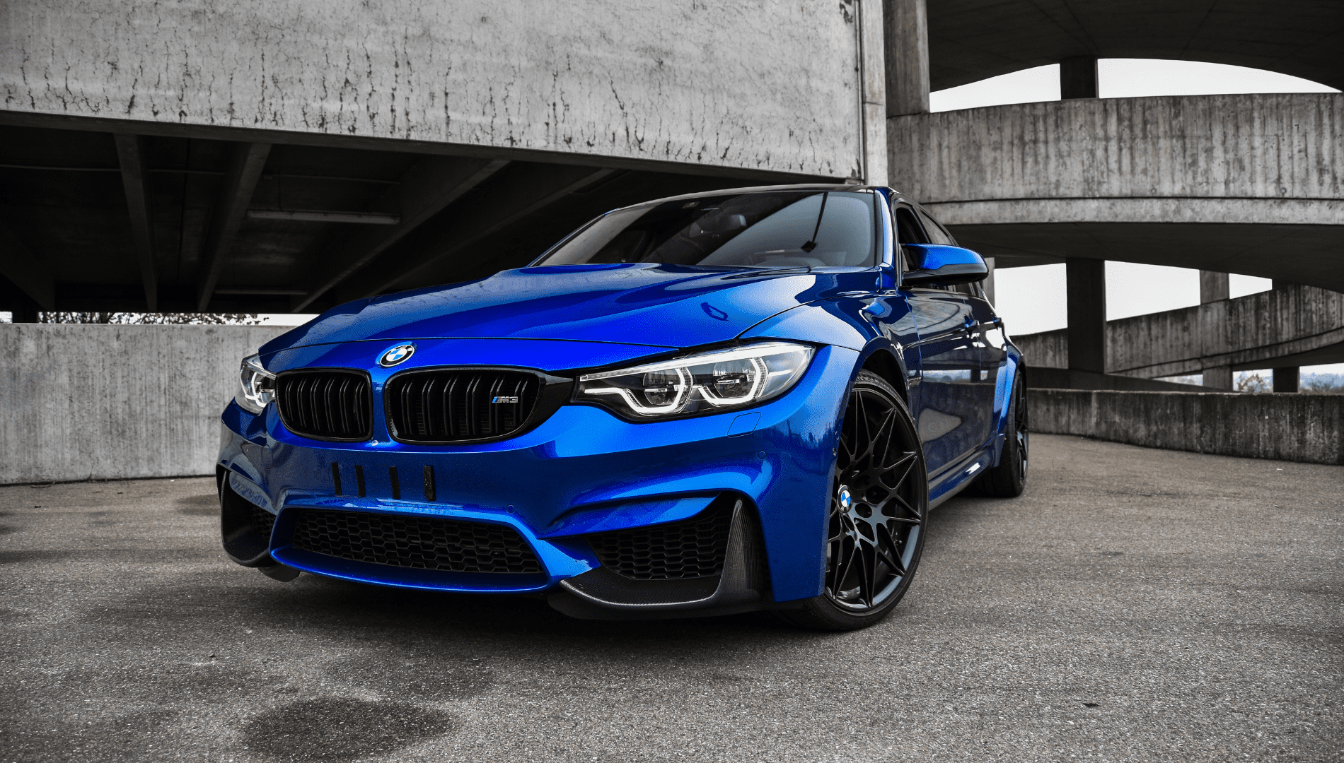 Blue BMW sports car parked in a concrete garage, front view