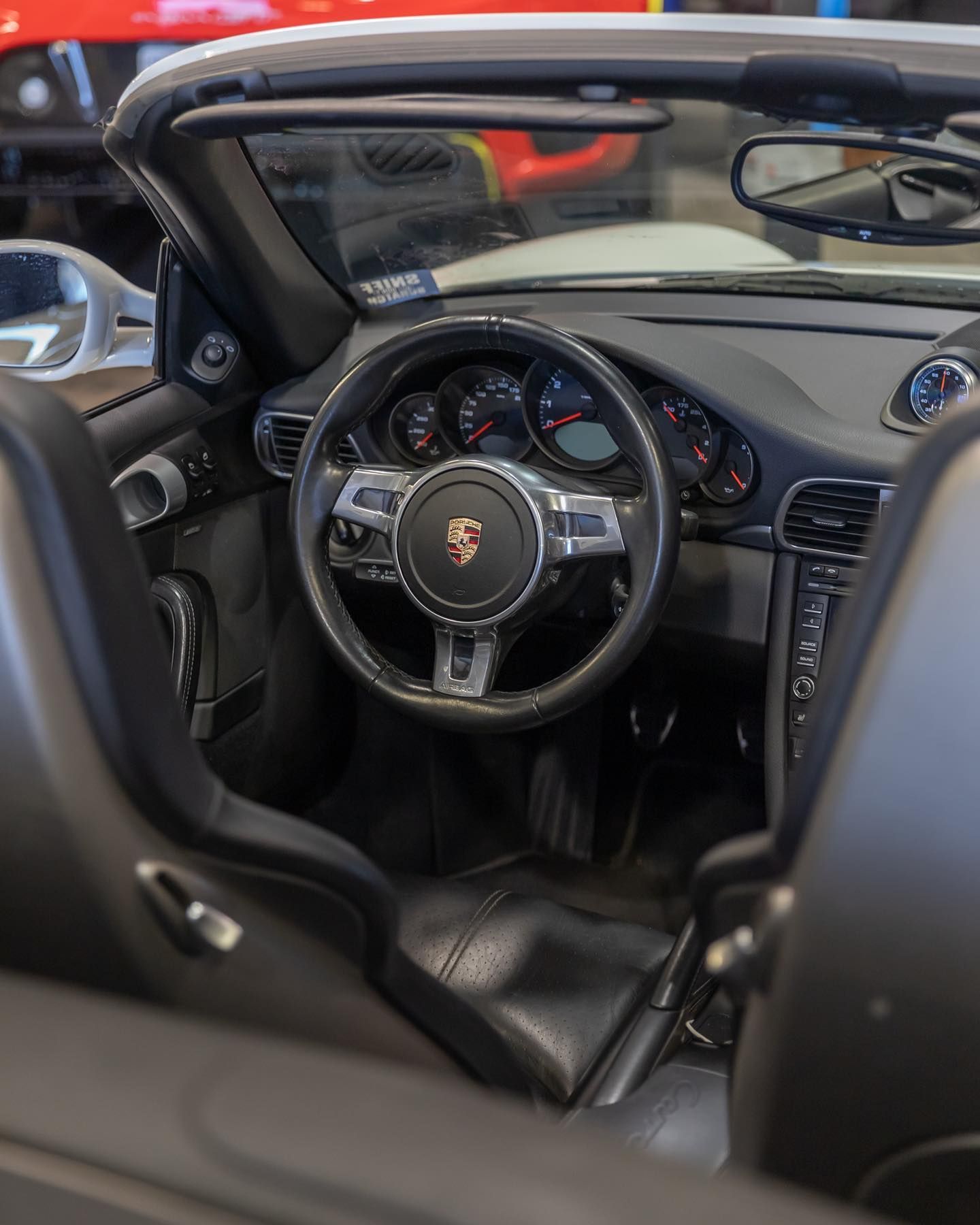 Luxury sports car interior with black leather seats, steering wheel, and dashboard, seen through an open door