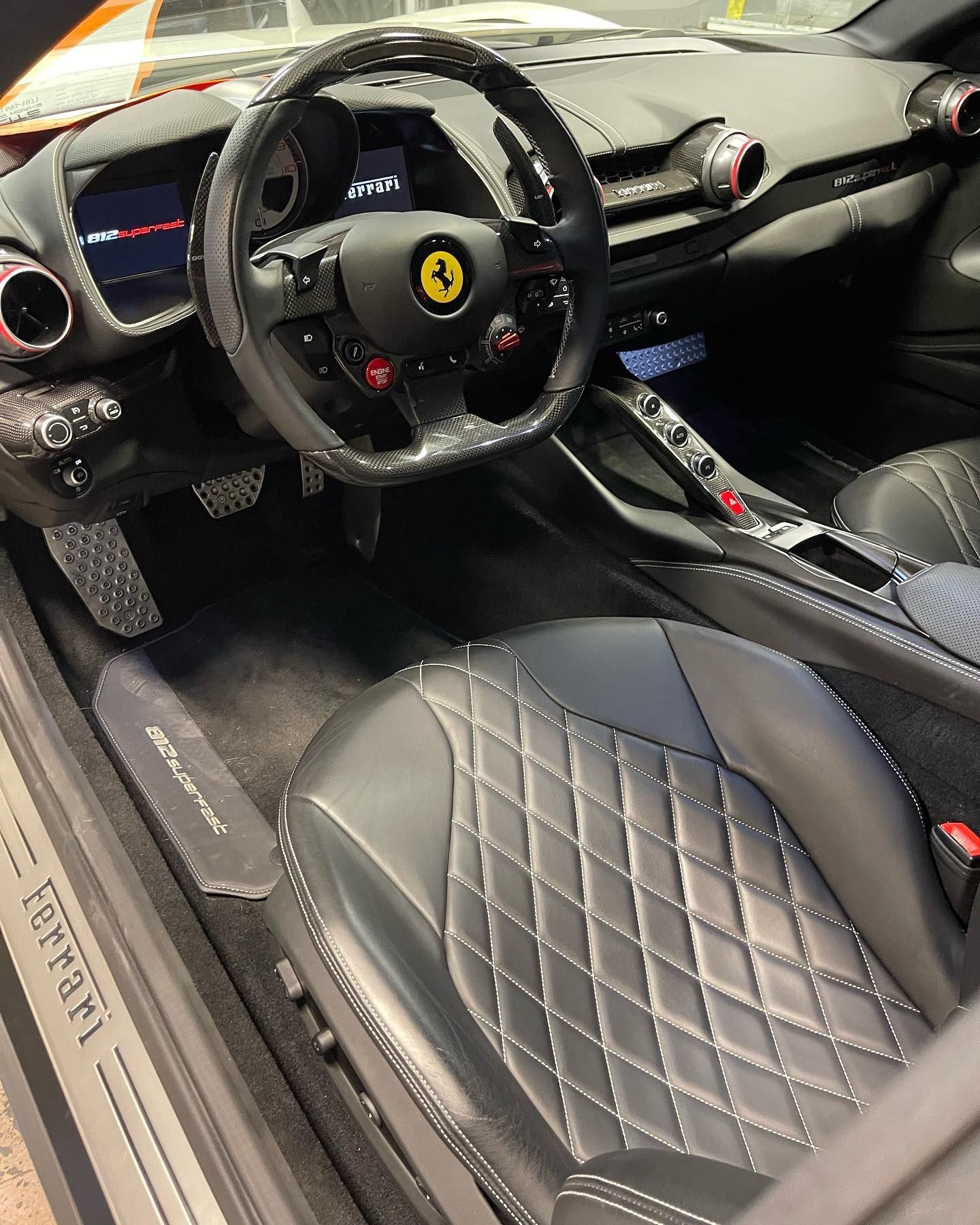 Luxury sports car interior with black leather diamond-stitched seats and Ferrari steering wheel