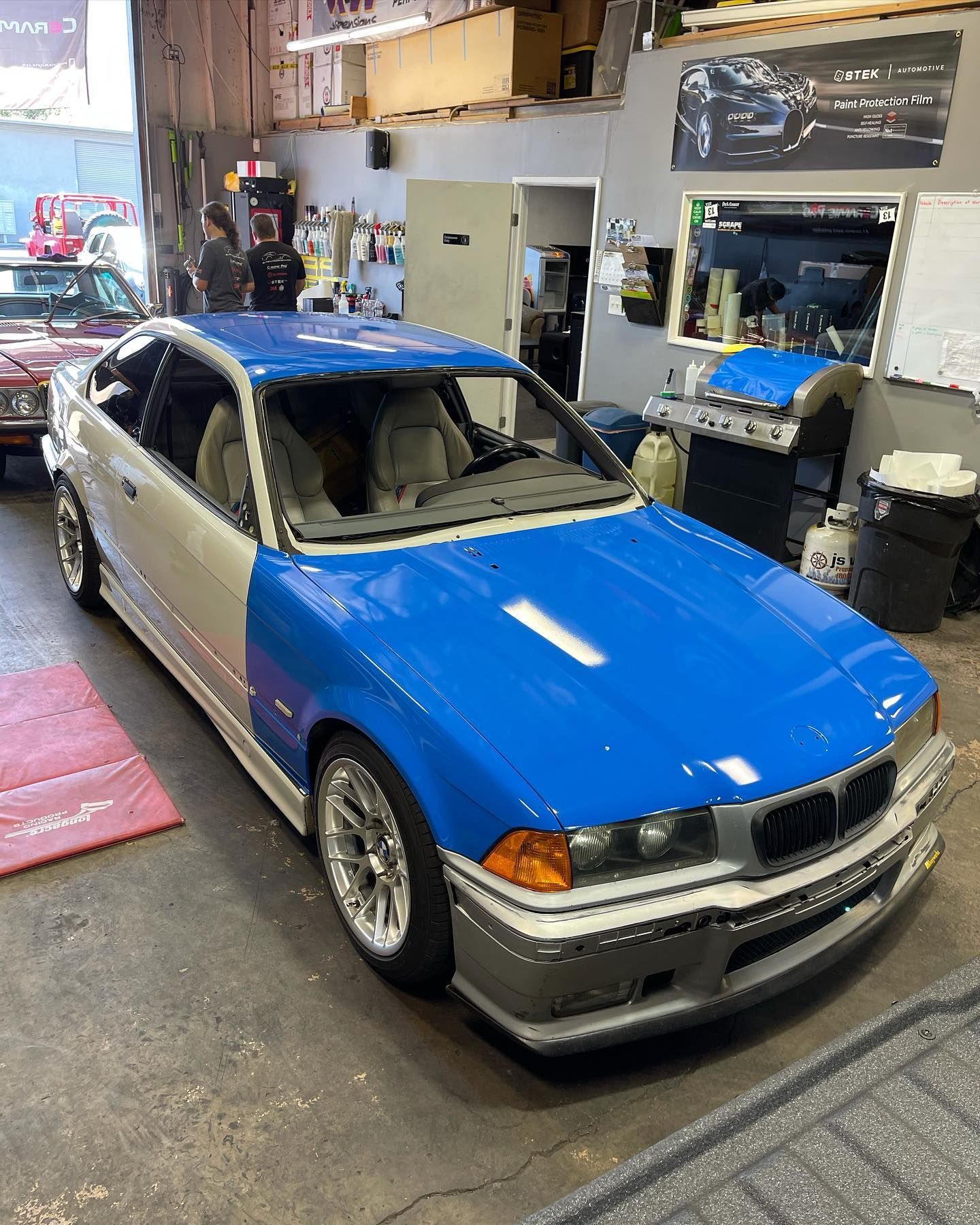 Blue and silver BMW coupe in an auto shop with its hood open