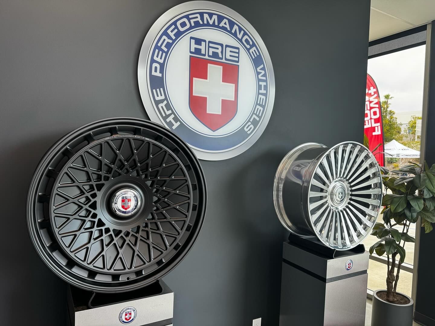 Display of alloy wheels and HRE Performance logo in a showroom setting