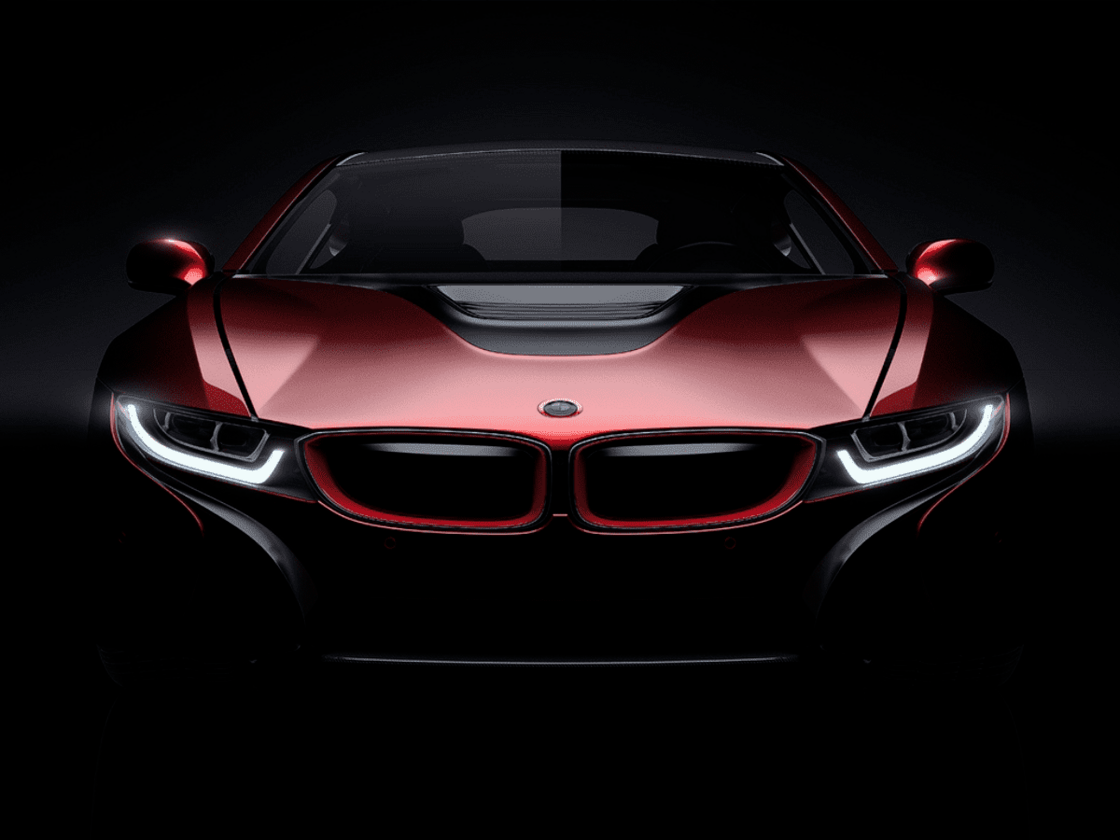 Front view of a red sports car with glowing headlights against a black background