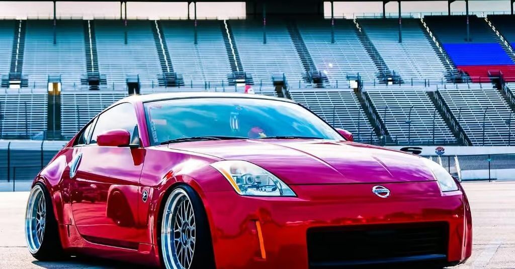 Red sports car parked on a racetrack with empty stadium seats in the background