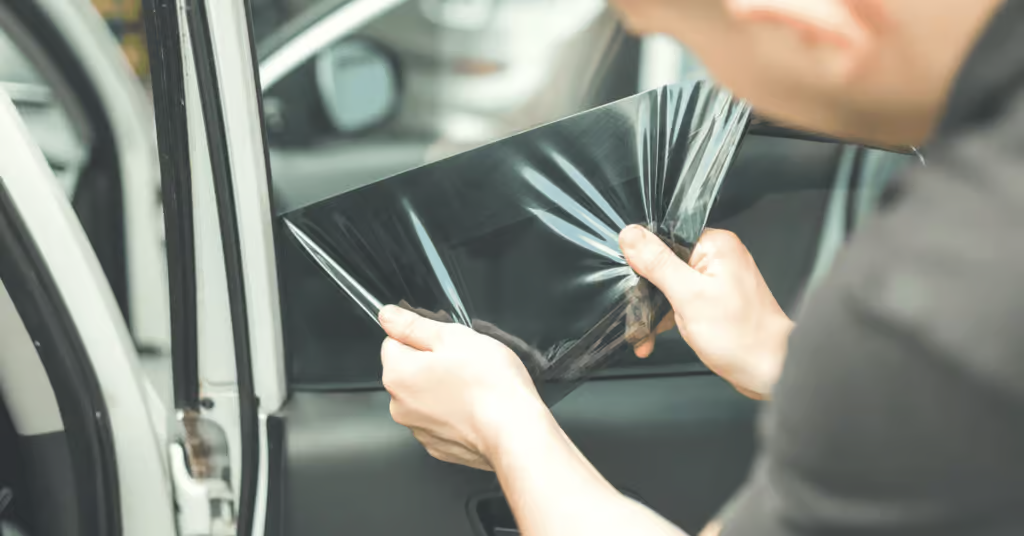 Gloved hand polishing a black car hood in a garage