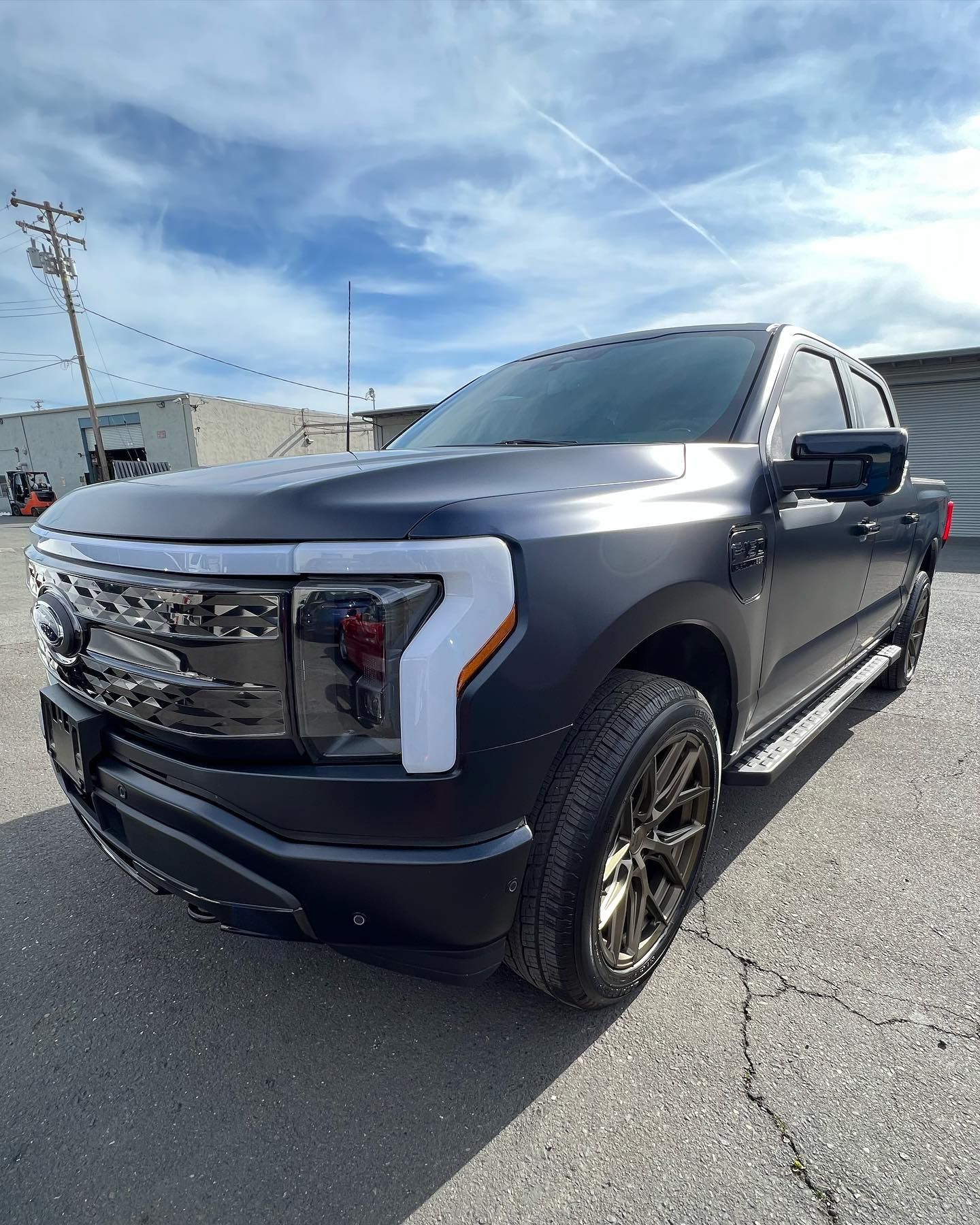 Dark gray pickup truck parked outdoors on gravel under a bright blue sky