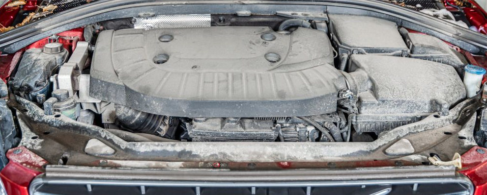 Flood-damaged car trunk with mud-covered spare tire well and debris under the rear hatch