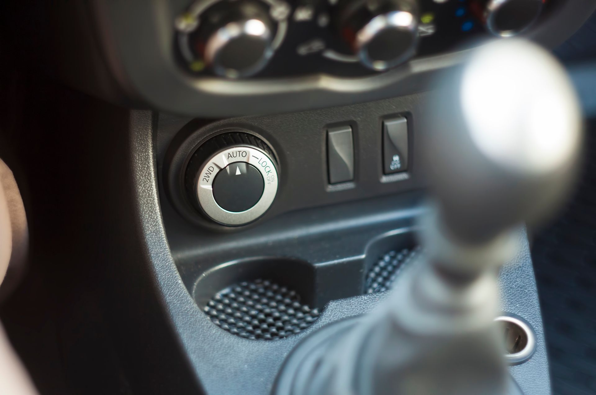 Car dashboard center console with climate controls and a gear shift in the foreground