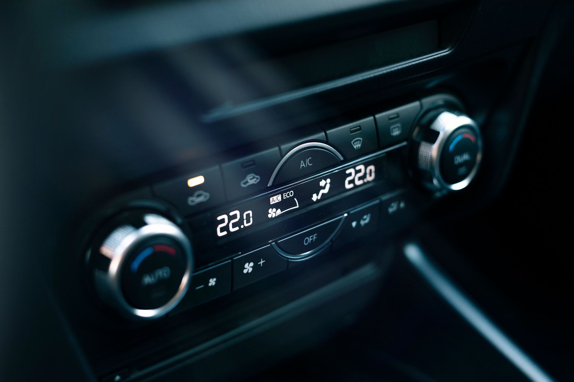Car dashboard climate control panel with digital temperature display and illuminated knobs
