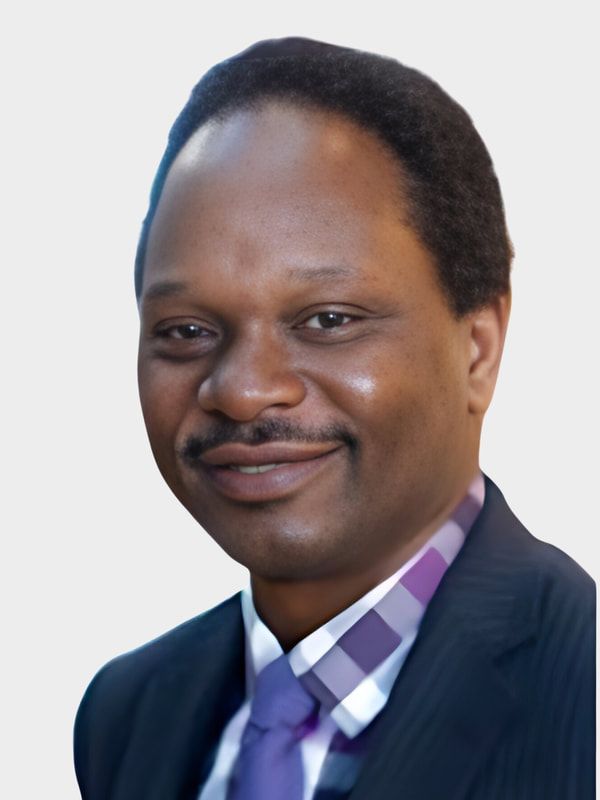 Studio headshot of a smiling person in a dark suit, purple checkered shirt, and lavender tie.