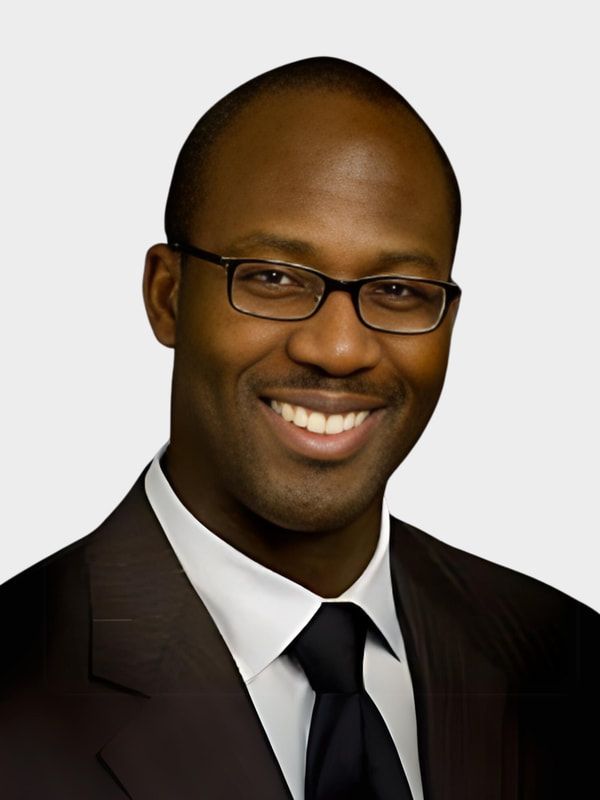 Smiling man in a dark suit and glasses on a light gray background