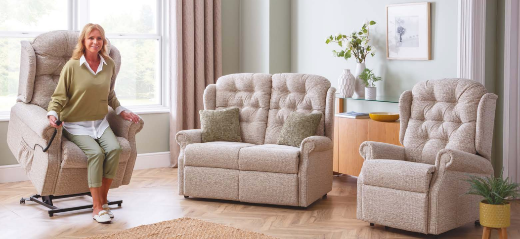 Living room with two beige tufted chairs, a side table, plant, and a person sitting by a bright window