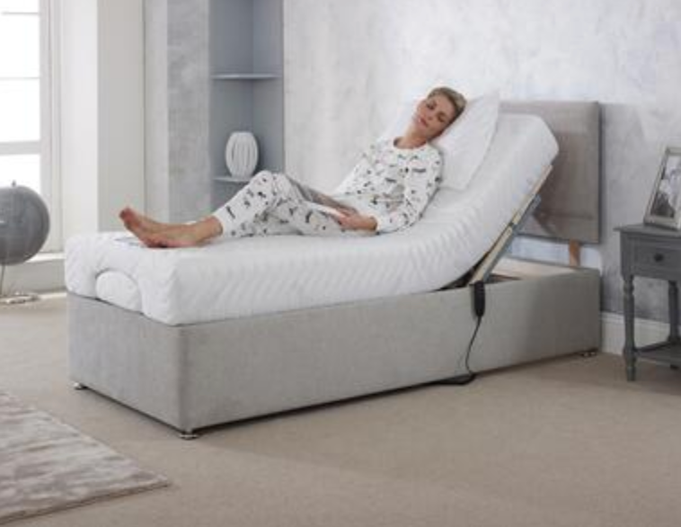 Person reclining on a white adjustable bed in a bright bedroom