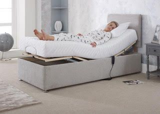 Person reclining in an adjustable bed in a bright bedroom, holding a tablet with the bed raised.