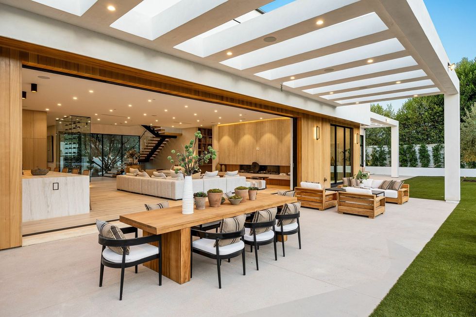 Il y a une grande table et des chaises sur le patio d'une maison.