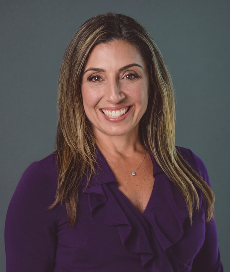 Smiling woman in a purple blouse against a dark gray background