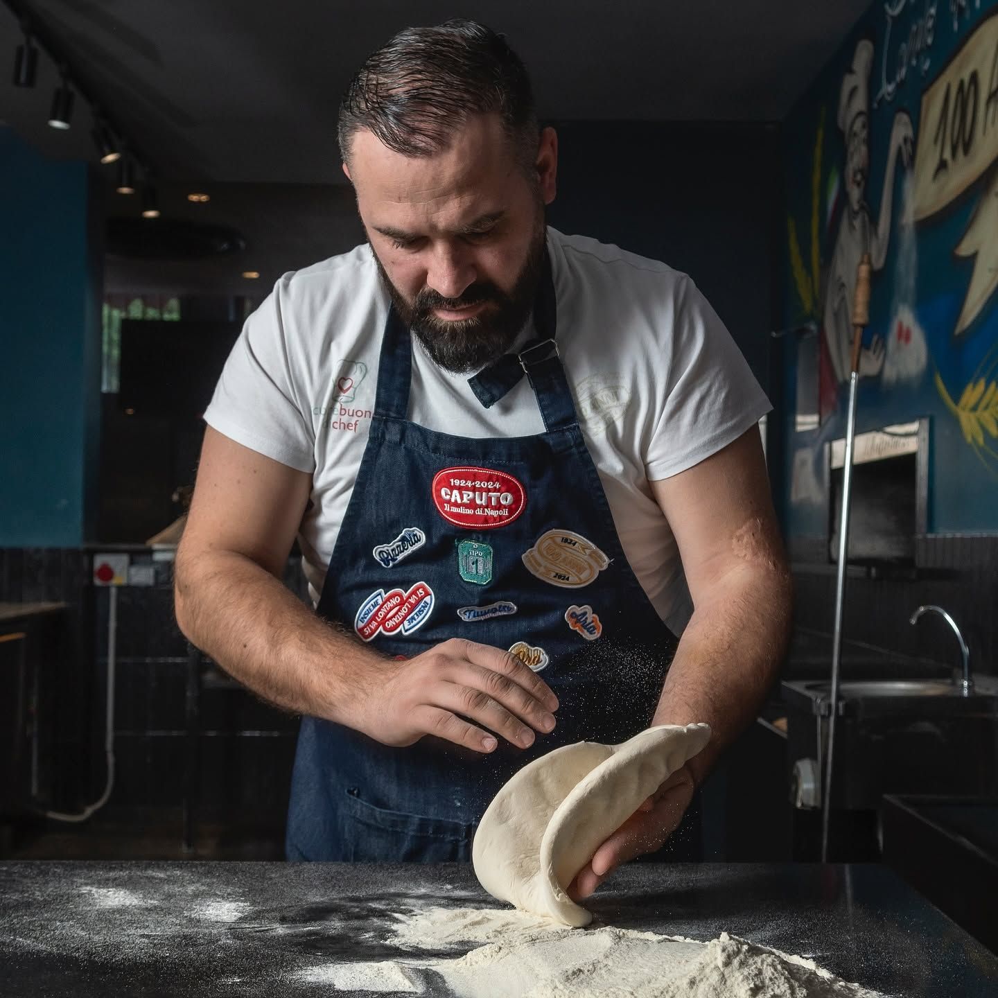 Chef che impasta su un piano infarinato in una cucina poco illuminata