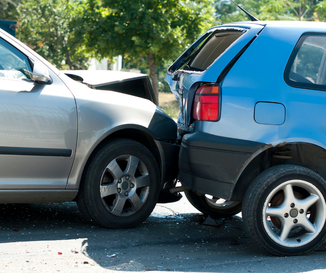 Blue hatchback and silver sedan after a rear-end collision on a sunny street.