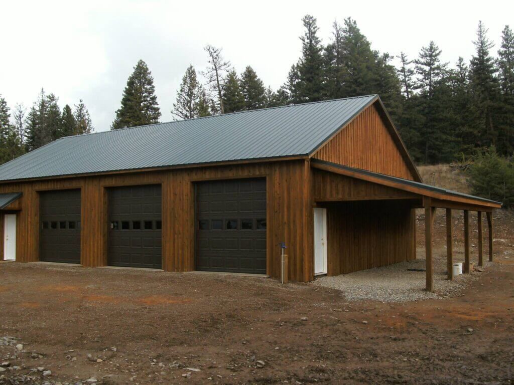 A wooden garage with a metal roof and black garage doors