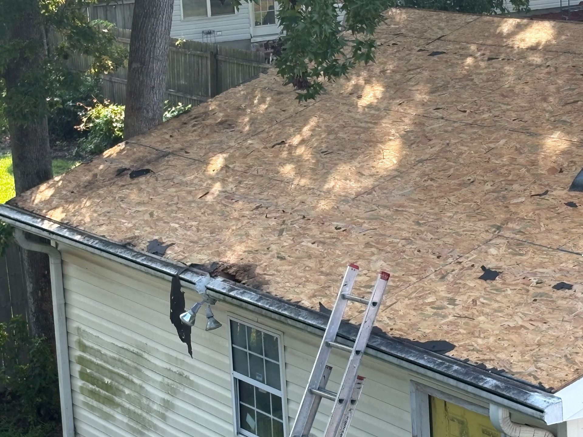 A Charleston Roofs and Windows inspection manager reviewing a line-item roof replacement estimate with a Hollywood, SC homeowner on the front porch of a country home, with a new standing seam metal roof overhead and pine trees along the property line. The image represents roof replacement cost in Hollywood, SC, priced per square for asphalt shingles, metal and flat roofs, with free inspections and 0% financing for 12 months on approved credit.