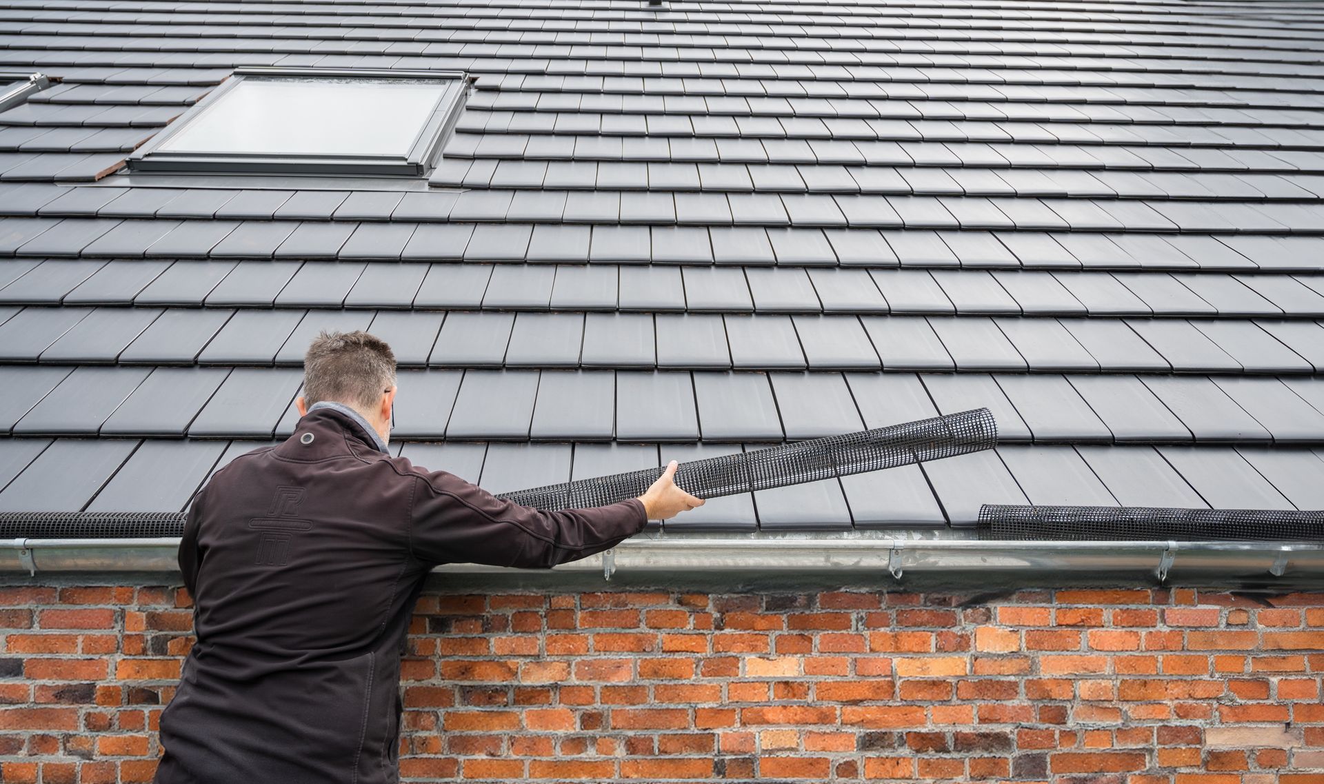 A man installs a roof gutter.
