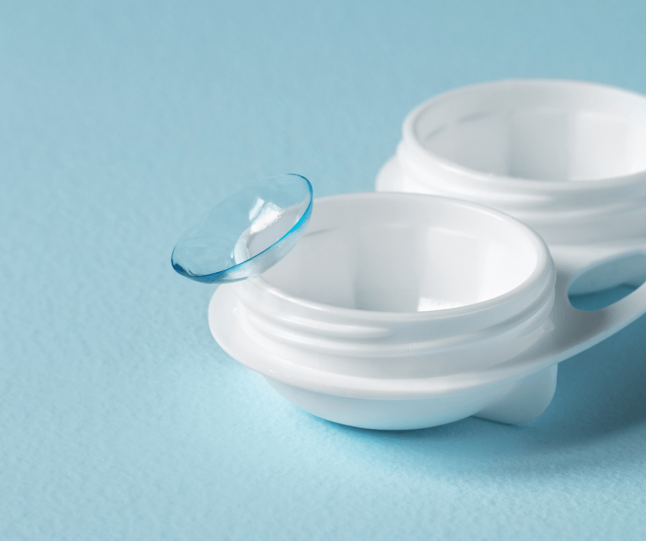 Two white contact lens cases with a blue contact lens on a light blue background