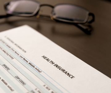 Health insurance form beside eyeglasses on a desk