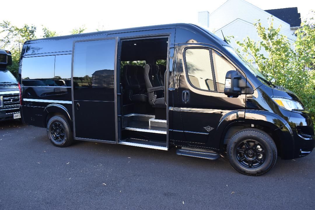 A black van with the door open is parked in a parking lot.