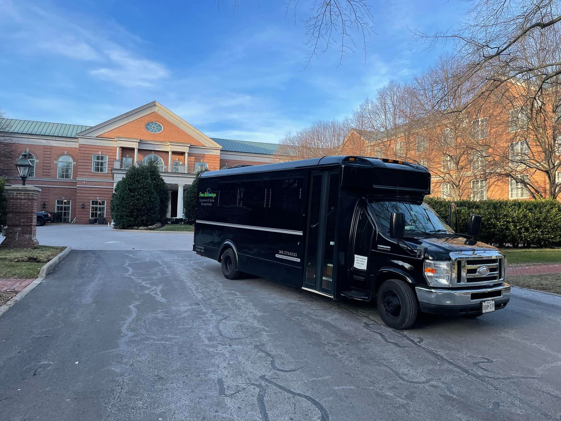 A black van is parked in front of a large building.