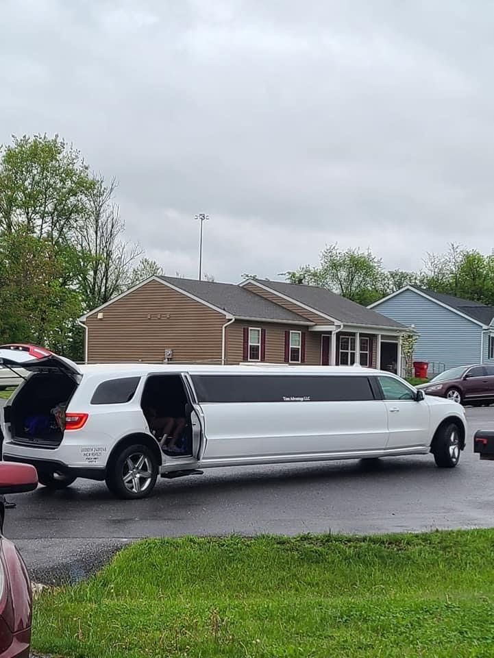 A white limousine is parked in a driveway in front of a house.