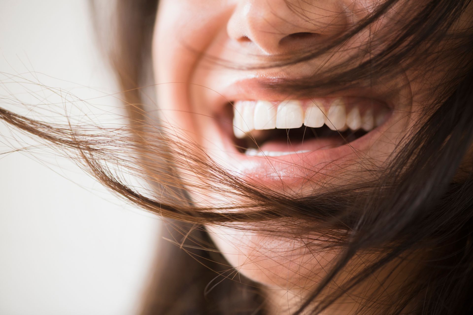 Primo piano di una bocca e di un naso sorridenti, con i capelli che vi svolazzano sopra.